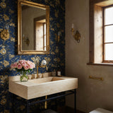 A beige travertine console sink with a rectangular basin, supported by a black metal stand and paired with brass fixtures in an elegant bathroom setting.
