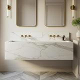 A Calacatta Gold marble floating trough sink with soft gold veining, designed as a double vanity with clean lines and wall-mounted brass fixtures.
