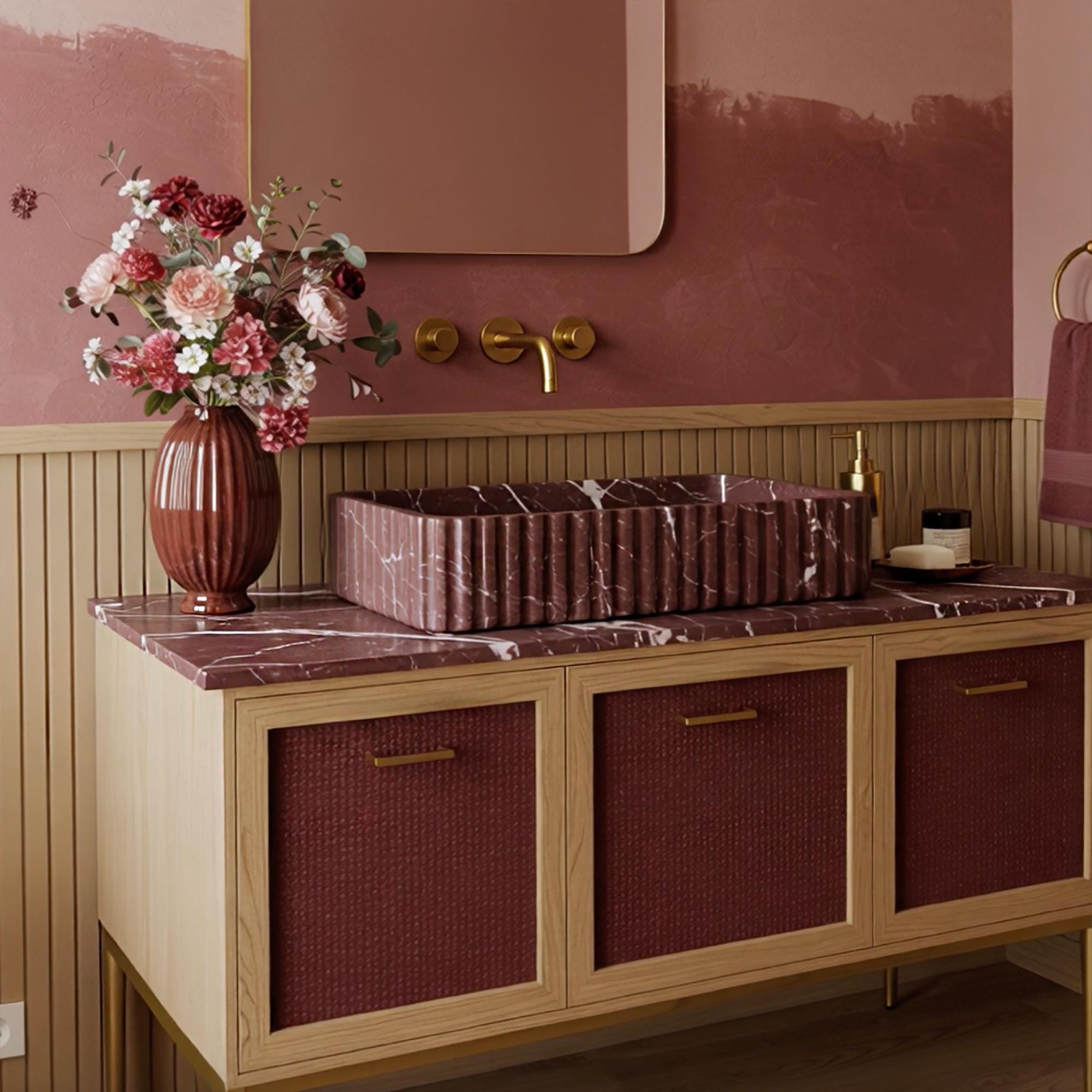 A fluted Rosso Levanto marble vanity with expressive veining, finished with burgundy rattan cabinet doors and subtle brass hardware.
