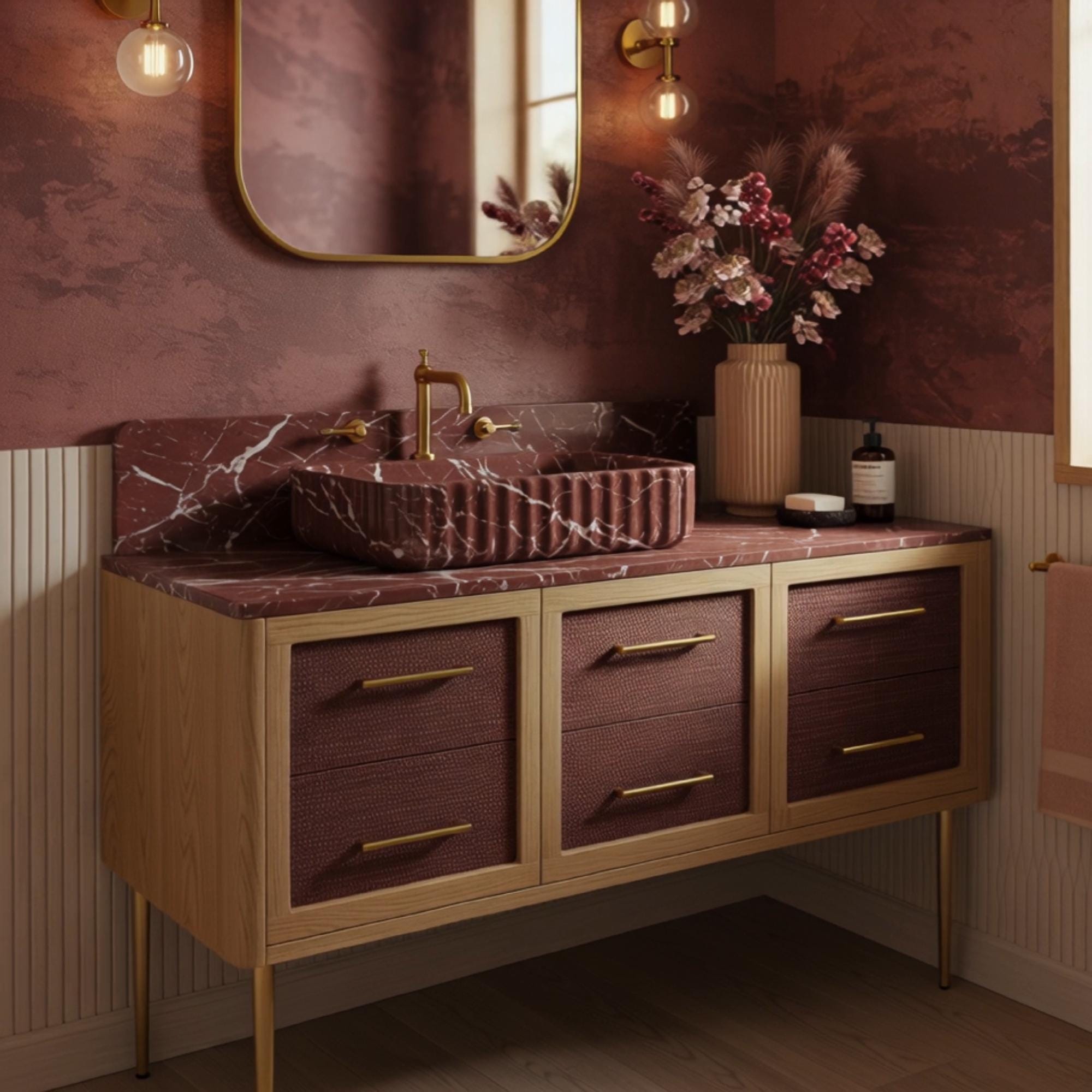 A sculptural Rosso Levanto marble vanity with a fluted stone basin, presented on an Art Deco console in a luxury bathroom space.
