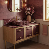 A fluted Rosso Levanto marble vanity with deep burgundy veining, paired with an Art Deco–inspired wood console and brass details in a refined bathroom setting.
