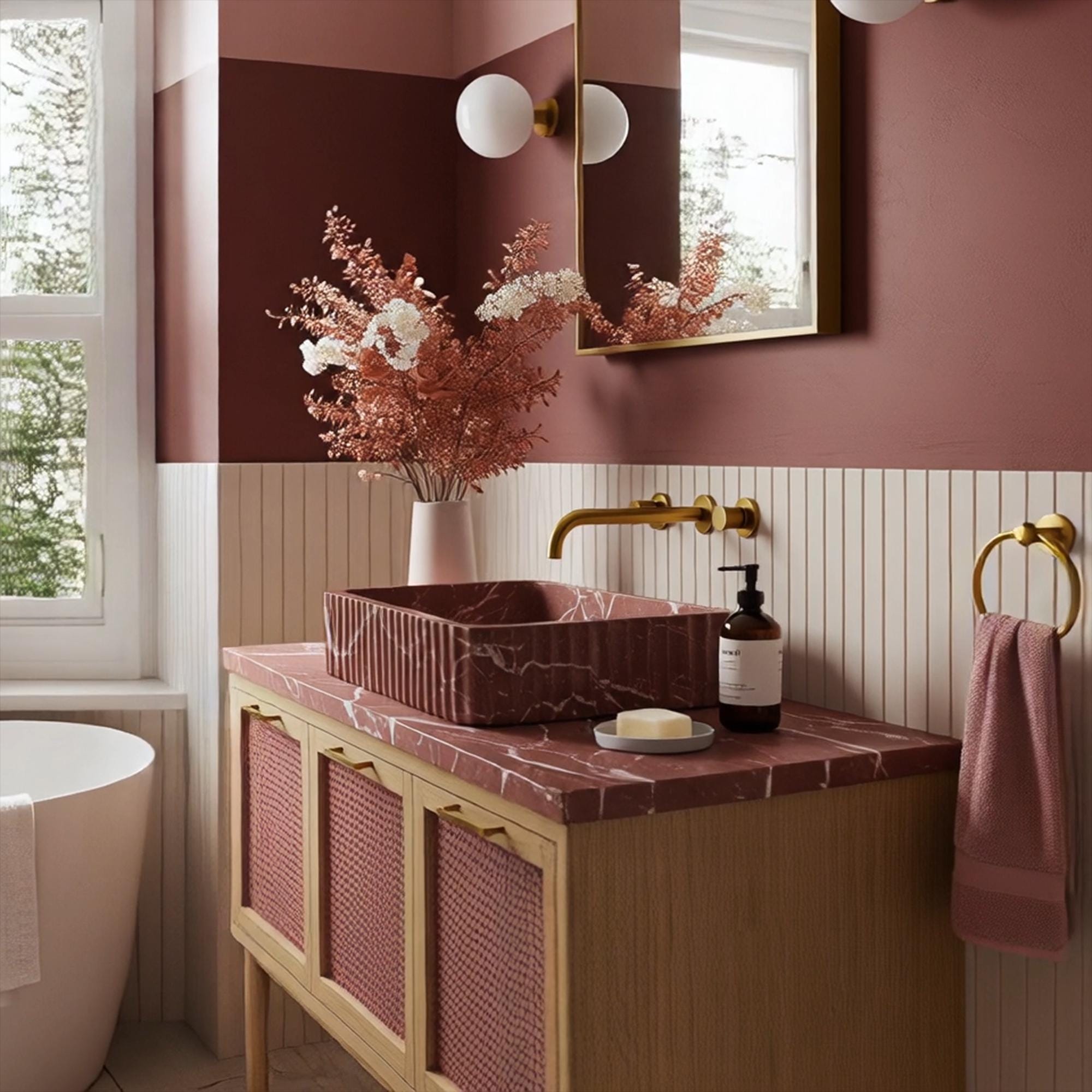 A fluted Rosso Levanto marble sink set on a pink rattan cabinet, highlighting expressive veining and sculptural detailing in a sophisticated space.
