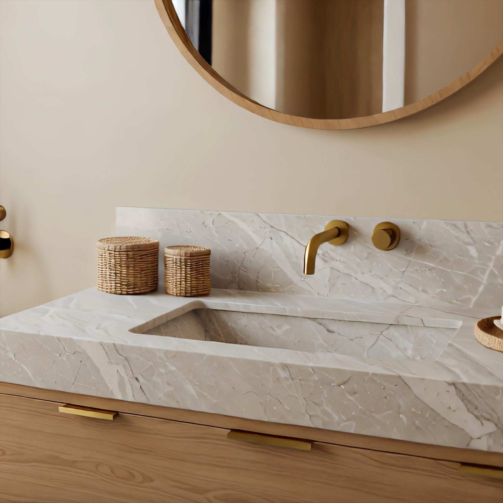 A Tundra Grey marble sink vanity with integrated basin, styled with an oak wood console and woven accessories in a serene, light-filled interior.
