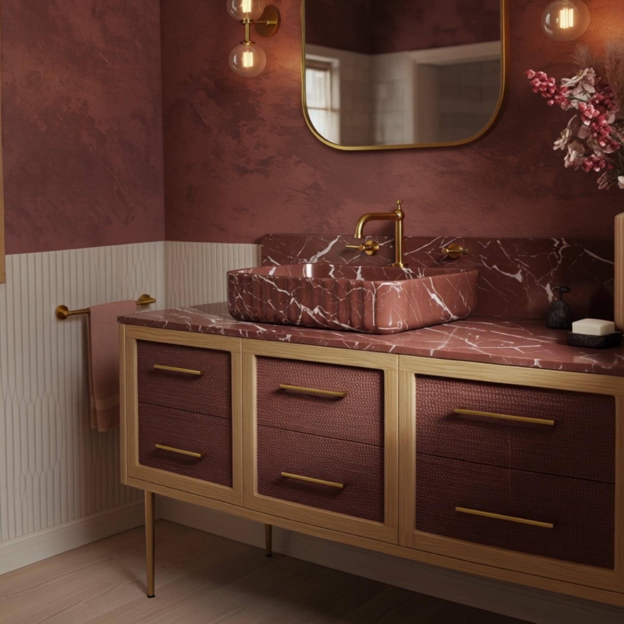 A Rosso Levanto marble vanity crafted from natural stone, featuring a fluted basin design and Art Deco console with brass hardware.
