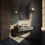 A Nero Marquina marble geometric console sink with bold white veining, supported by slender brass legs in an elegant bathroom setting.
