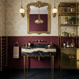 A Nero Portoro marble console sink with striking gold veining, supported by slender brass legs and styled with brass wall-mounted fixtures.
