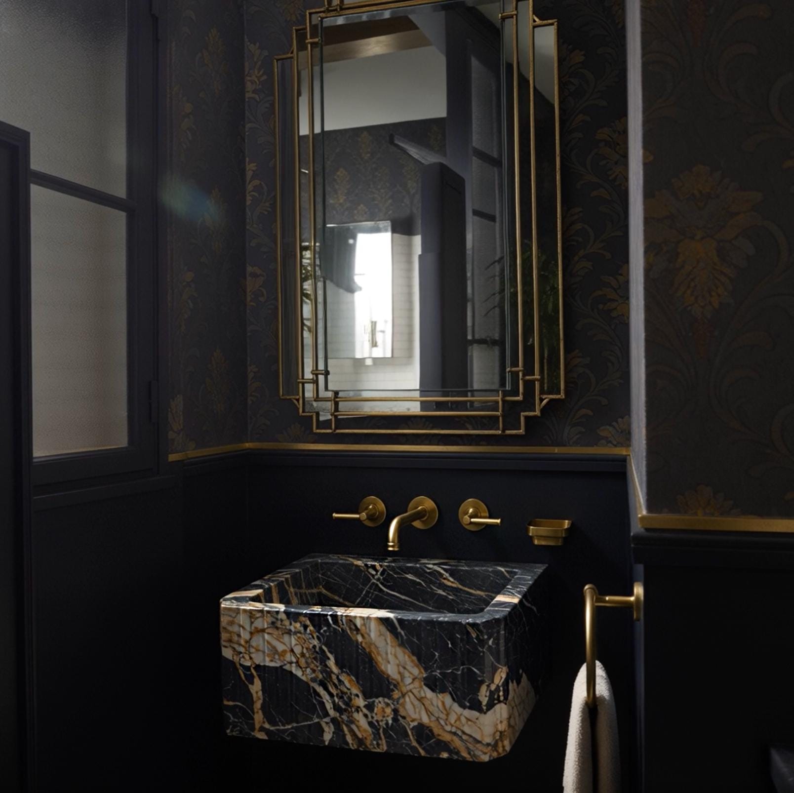 A fluted Picasso marble floating sink styled with brass fixtures, creating a dramatic focal point in a sophisticated bathroom.
