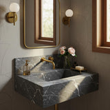 A Pietra Grey marble floating sink with a honed finish and integrated backsplash, featuring soft white veining and brass fixtures in a calm, elegant bathroom.
