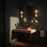 A striking Rosso Levanto marble vessel sink set on a travertine console with brass legs, perfect for luxurious powder rooms.