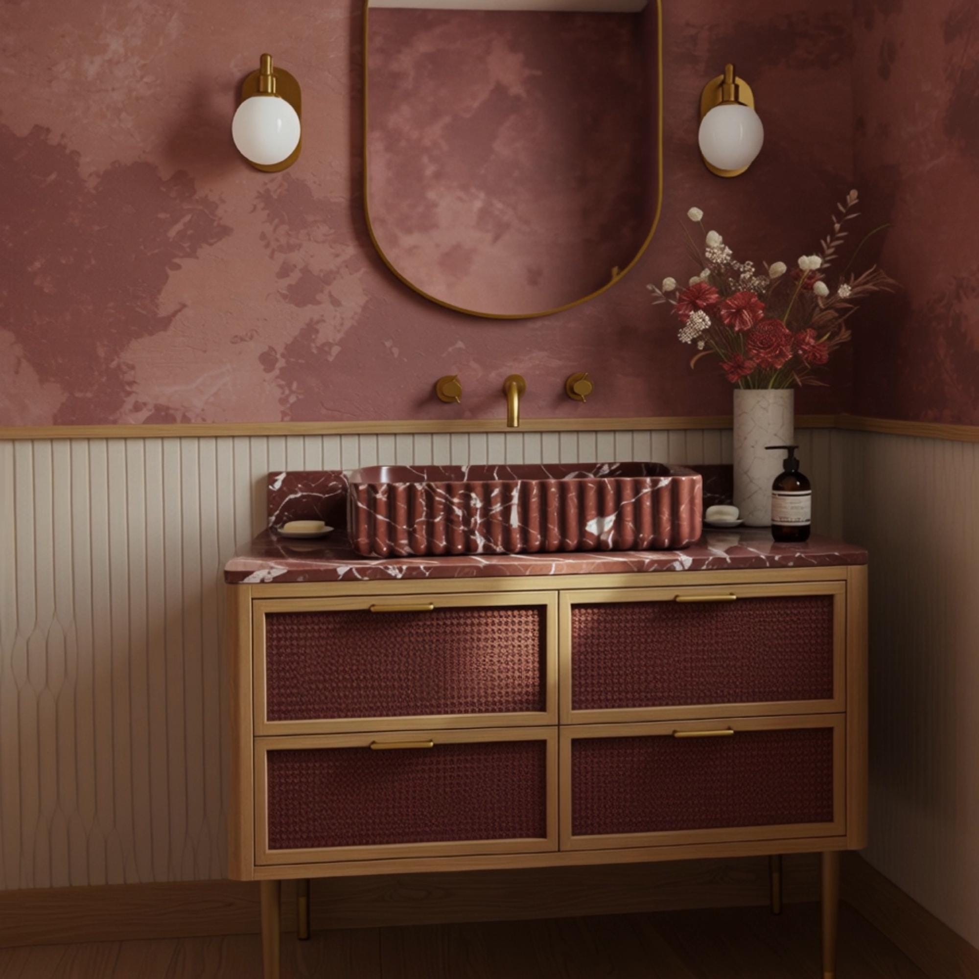 A Rosso Levanto marble vanity featuring a fluted stone vessel sink and rattan cabinet, offering a warm and elegant bathroom statement.
