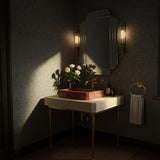 A Rosso Levanto marble vessel sink set on a beige travertine console, supported by slender brass legs in a softly lit, elegant bathroom.
