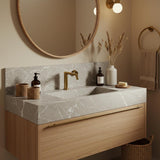 A Tundra Grey marble floating vanity with an integrated rectangular sink, featuring subtle white veining and an oak wood drawer in a calm, modern bathroom.
